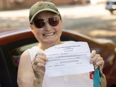 Woman smiling and holding her donation receipt. 